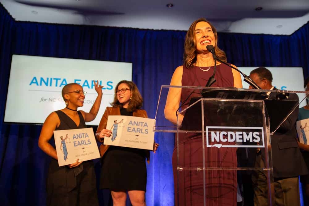  Anita Earls takes the stage at the North Carolina Democratic Party headquarters as her supporters cheer below. Juju Holton and Caroline Spencer, who both worked on the campaign, shed tears and celebrate behind her.  “We have a president who believes