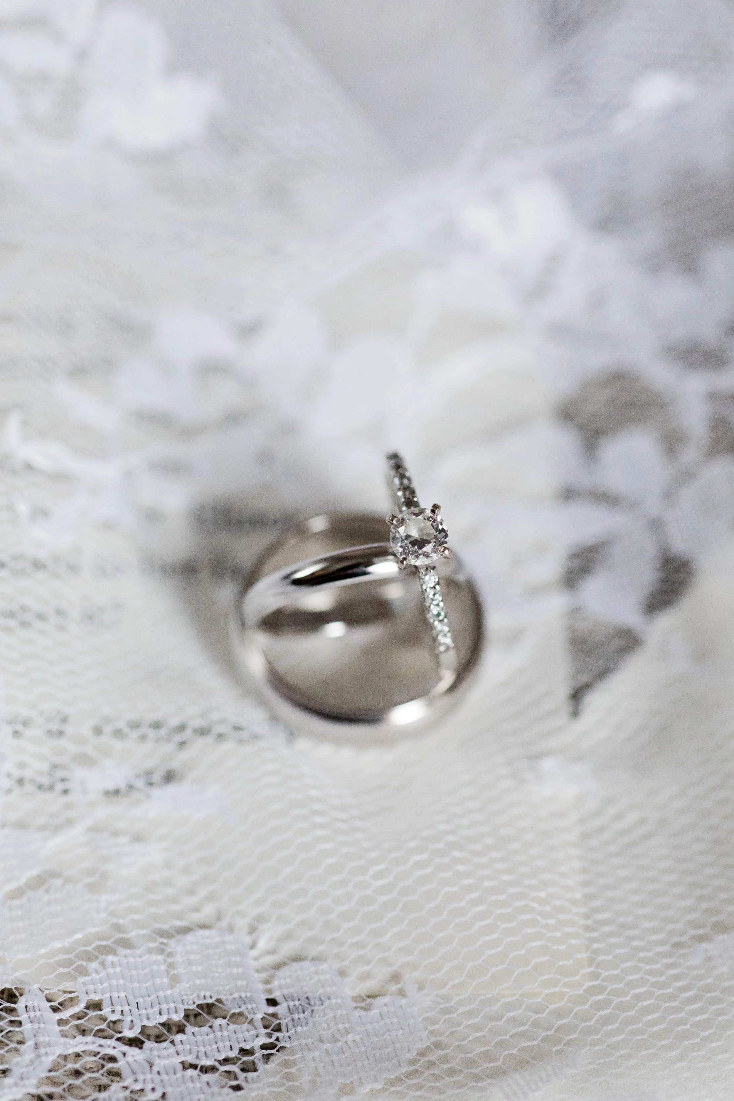 wedding bands and heirloom engagement ring from ford jewelers atop lace photographed by jaye kogut