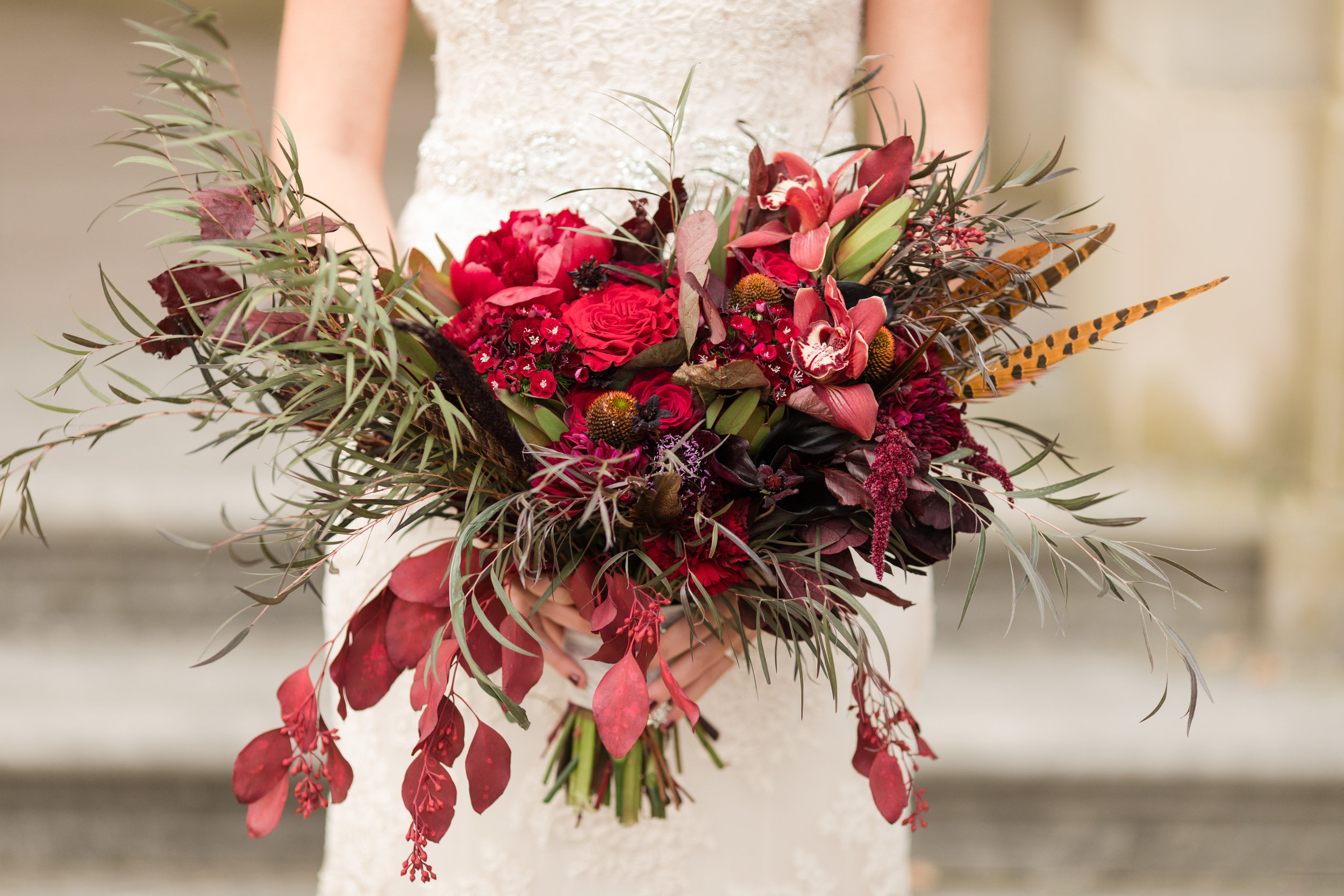 funky black and deep red bridal bouquet with whispy black leaves and feathers for alternative fall wedding