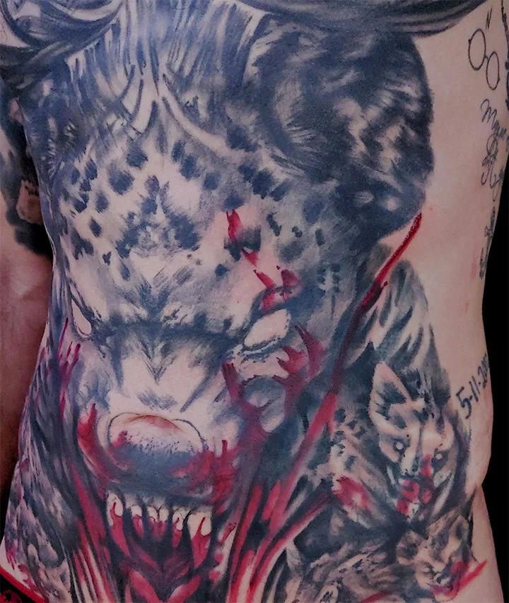 A trash polka tattoo in Spokane, Washington featuring a bar and red ink streaks on a mans chest and abdomen.