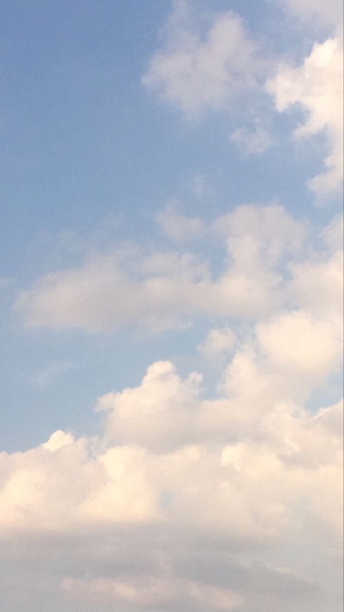 A sky filled with white and gray clouds, blue sky visible in between.