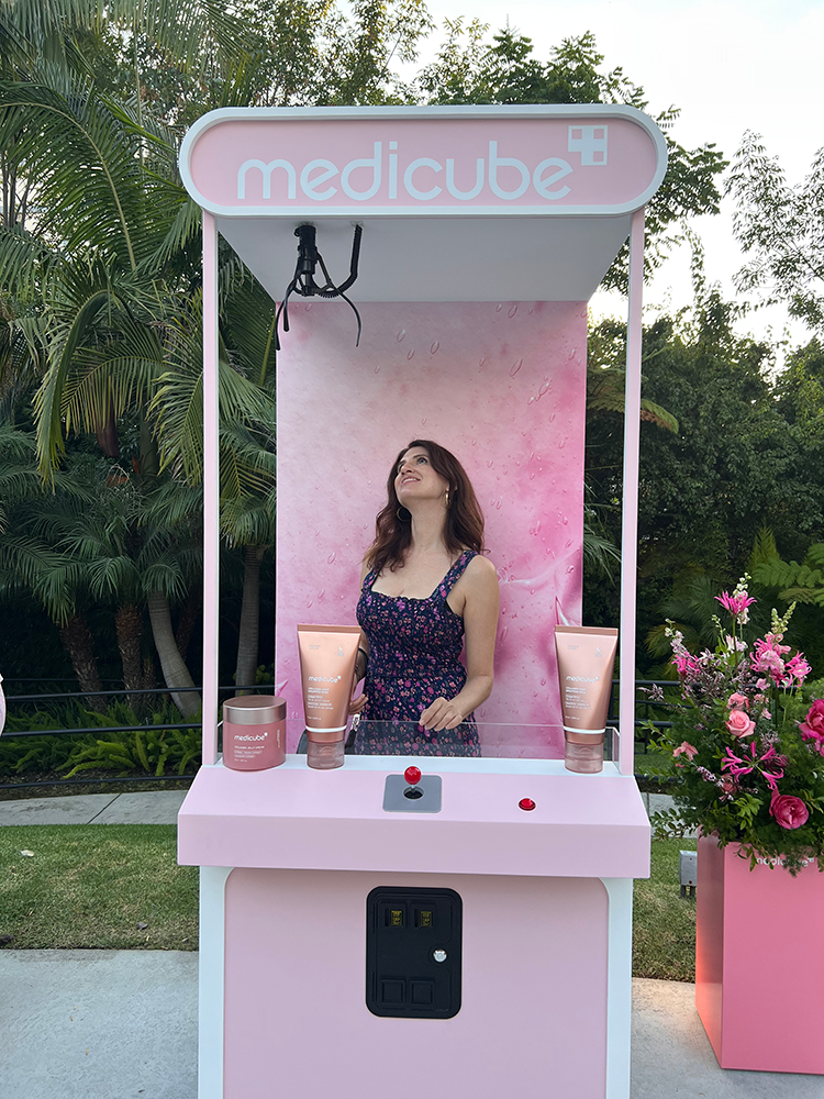 The writer, Lizzy, stands in a life-size medicube inspired claw machine and contemplates that world of K-beauty.