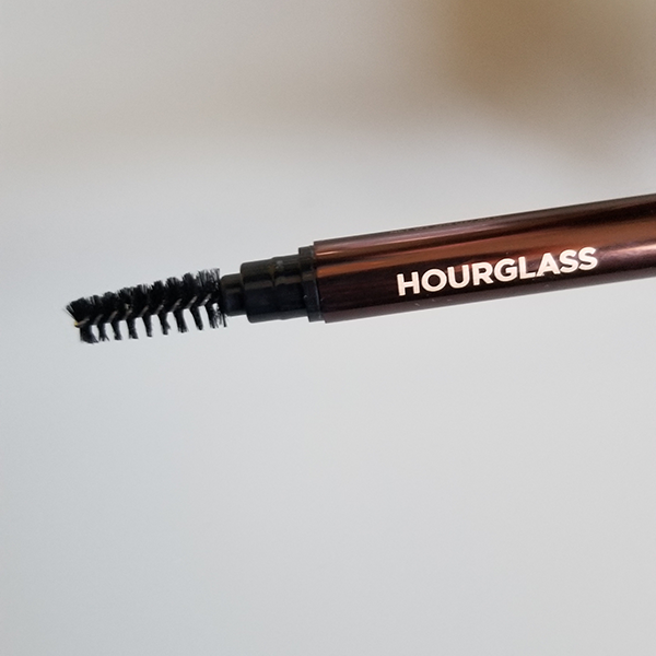 The Hourglass Arch Brow Sculpting Pencil features a brow brush for grooming and blending.