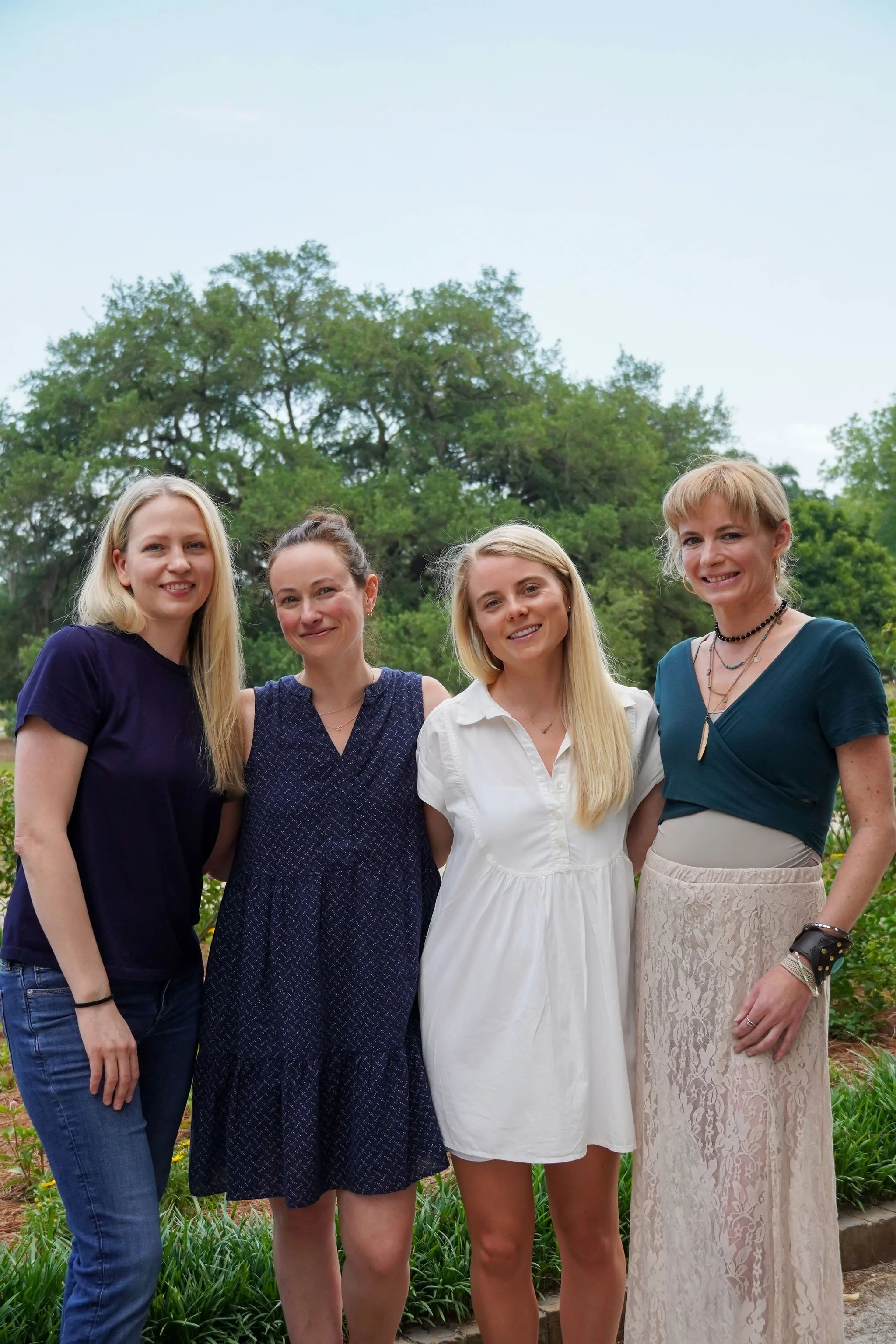 Four women posing in a park smiling at the camera