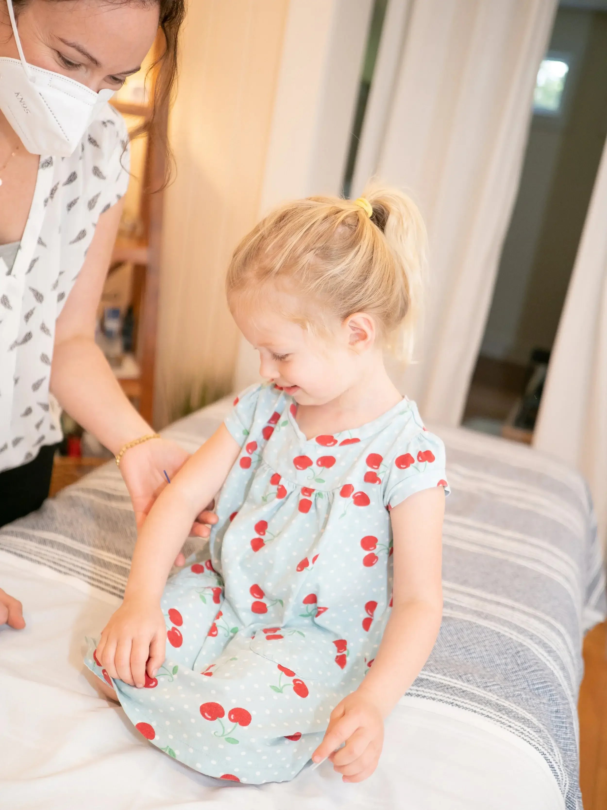 Girl with acupuncture needle in arm during pediatric TCM visit