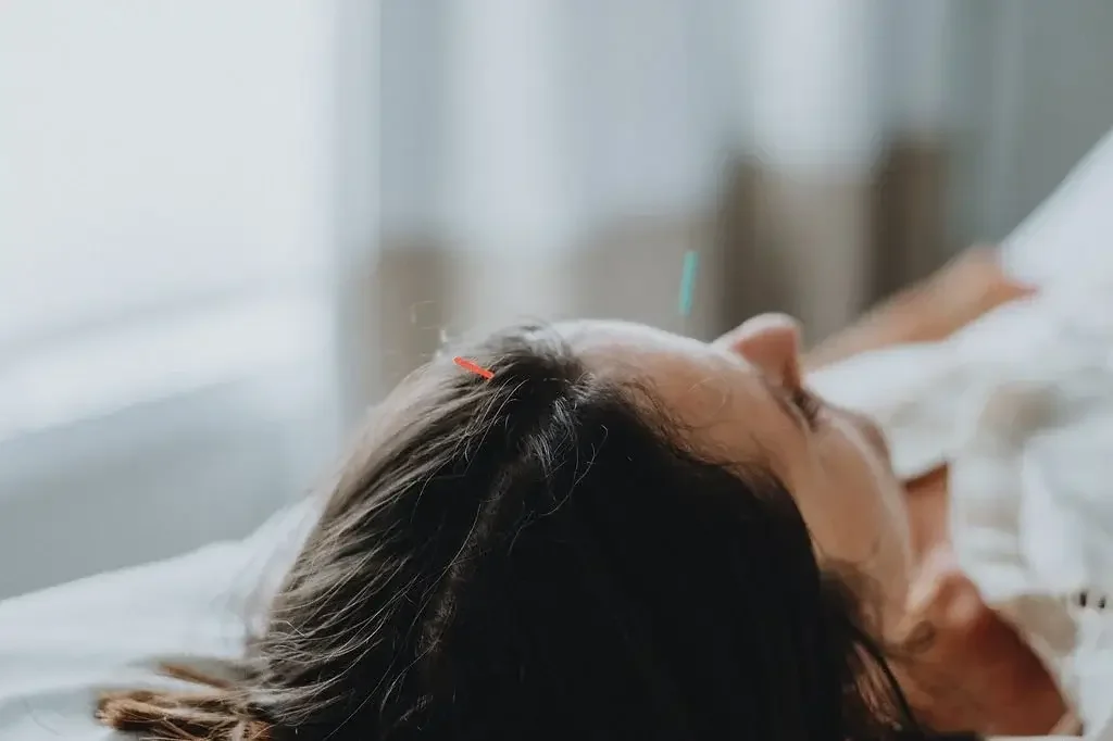 A medical professional performing moxibustion on a patient's lower legs in a peaceful clinic setting.