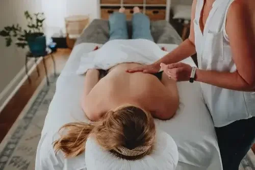 Person receiving cupping therapy treatment with glass cups placed on their back in a wellness setting.