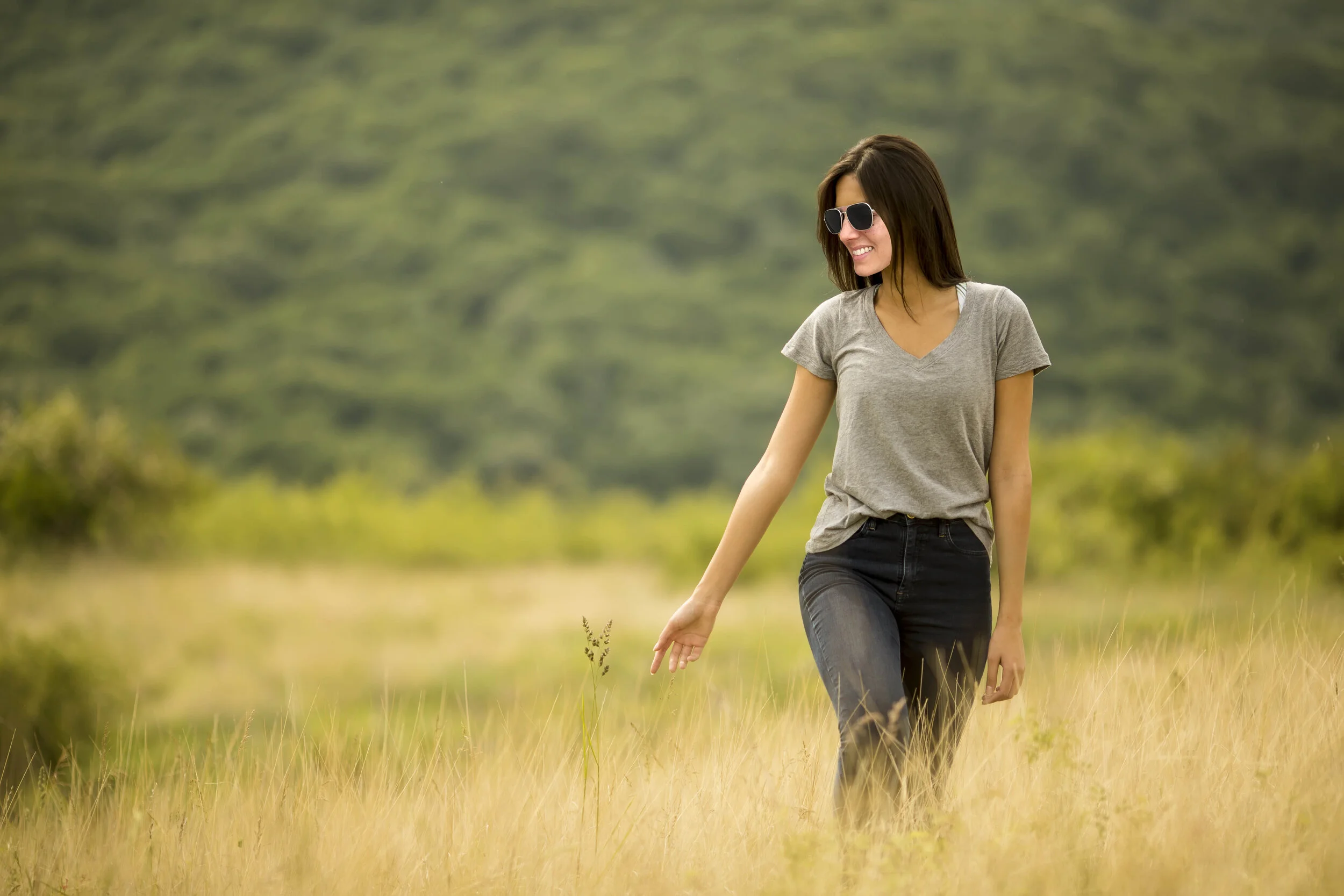 Young woman walking in the field of tall grass
