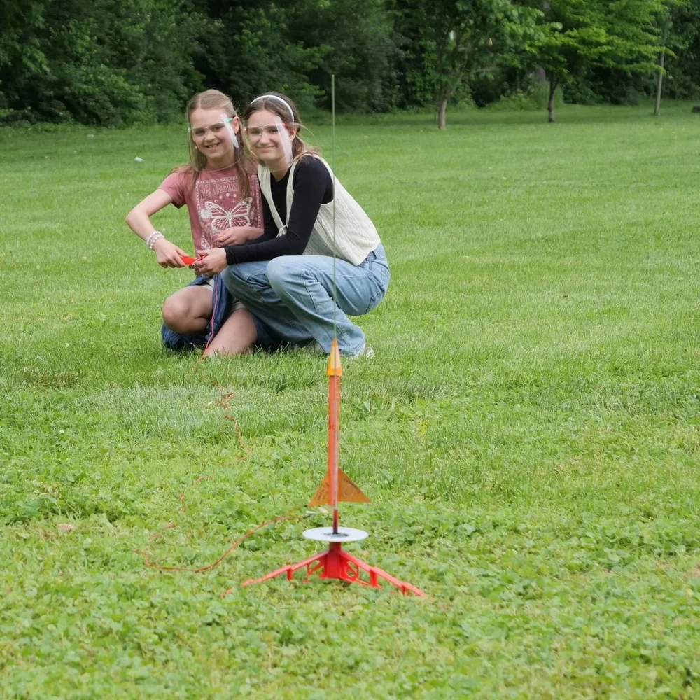 Two campers preparing a model rocket outdoors