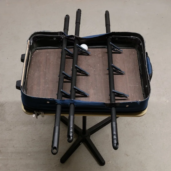 Chris Zacher Foosball table , 2018 Table, suitcase, wood, broom handles, clothespins and ping pong ball 30 x 22 x 30 inches