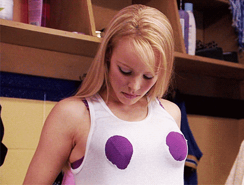 Regina movie scene gif of her staring down at her bra cutout tank top with a look of indifference. 