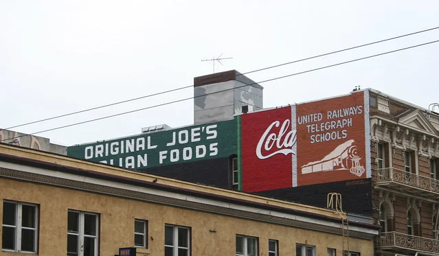 144 Taylor. Refurbished by Precita Eyes Murals, this project was funded by a Community Challenge Grant and overseen by the Tenderloin Housing Clinic. From the layering of the signs it would seem the United Railways Telegraph Sign is more recent than the Coca Cola sign. Not sure when/how the Original Joe's sign factors in but the restaurant was founded in 1937.I love this pic of the signs pre-refurbishing.