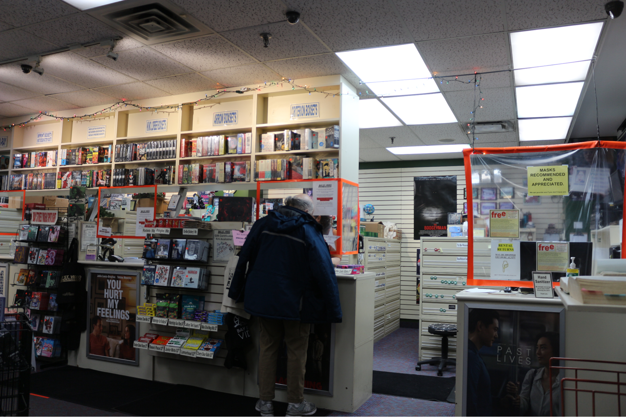  A customer rents a DVD from Bay St Video counter and an array of DVDs can be seen around the counters. 