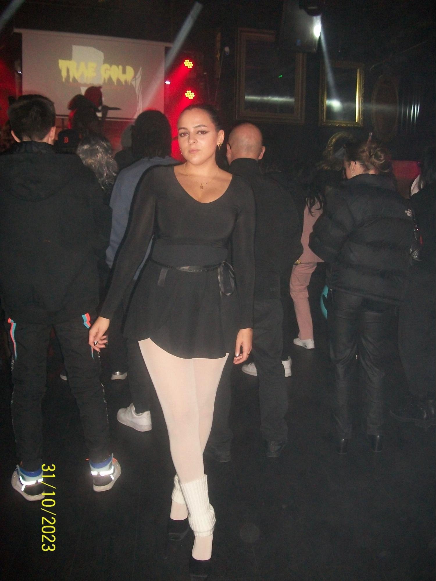 A woman poses in front of a crowd in a ballerina costume.