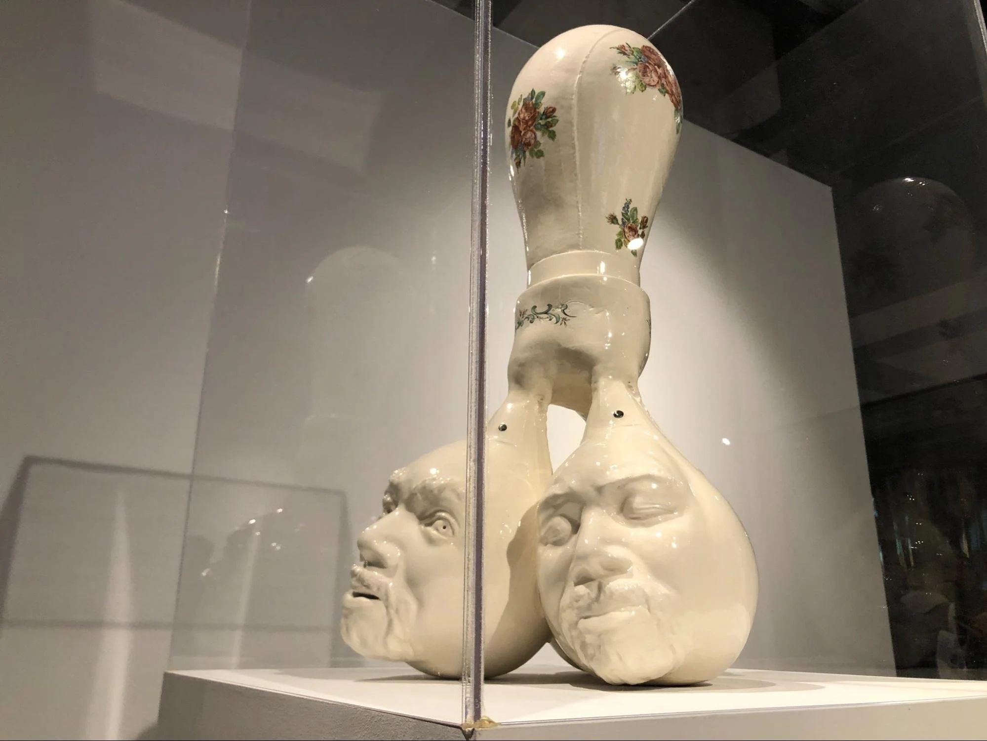 Sculpture of three porcelain heads in display case