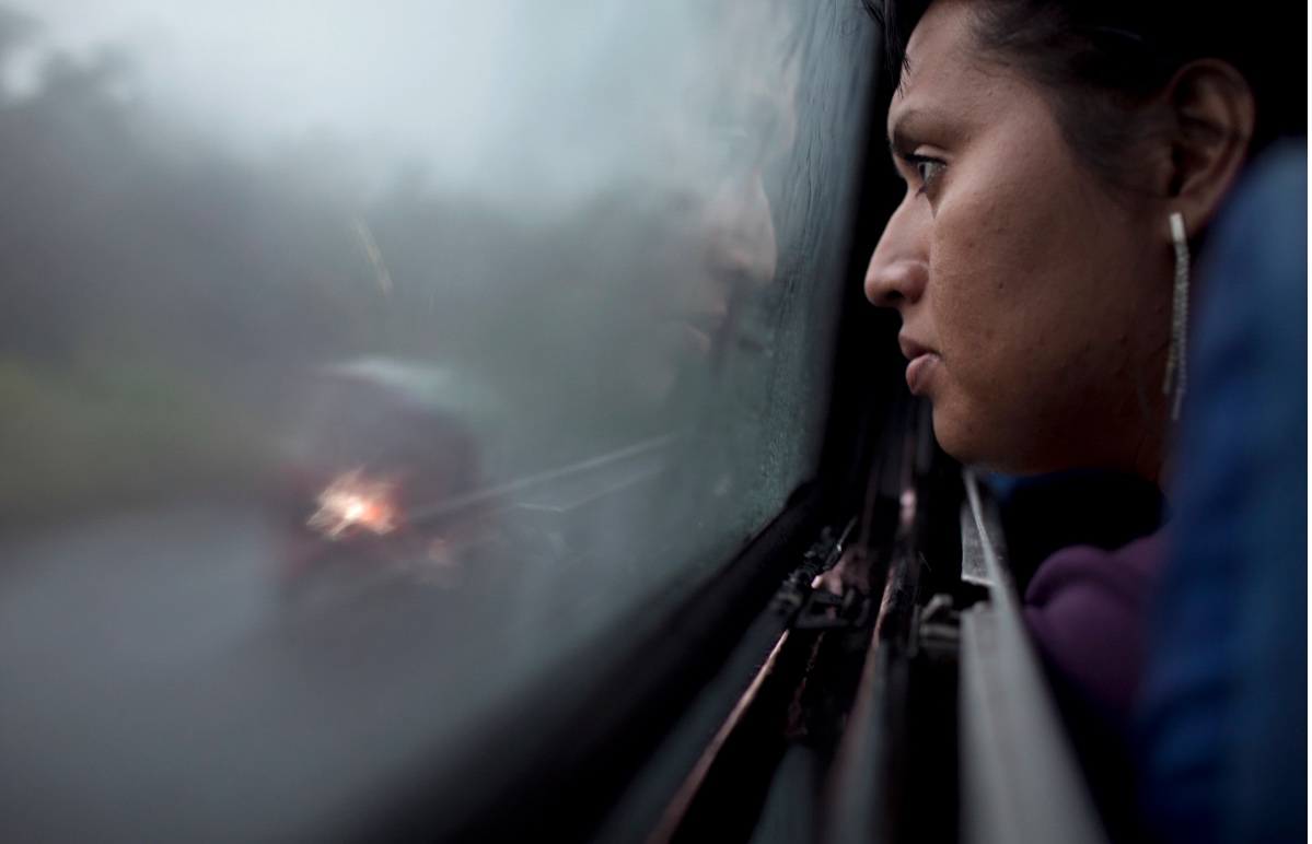 As dawn arrives, Marfil Estrella looks out the window of the bus that will take her from San Salvador, El Salvador to Guatemala City, Guatemala. Photos by Danielle Villasana .