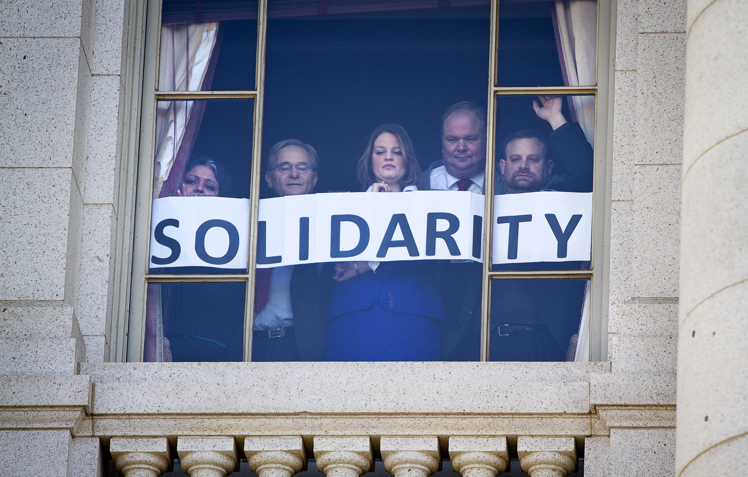 MADISON, WI — FEBRUARY 24: Employees inside the Wisconsin State Capitol show a message of support and solidarity from their window looking over the worker and labor union opposition rally just outside. Workers and labor unions rallied in opposition to a right-to-work bill being discussed in the state legislature. 