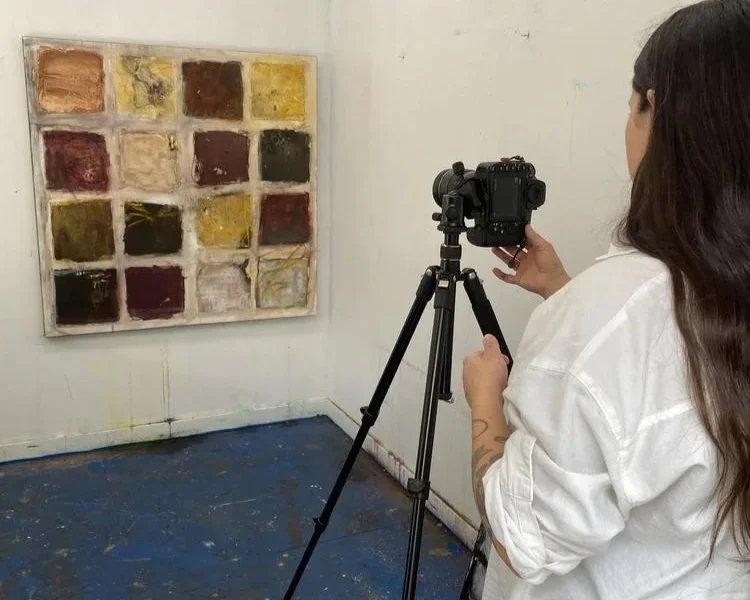 "Photographer Stephanie Artuso using a tripod-mounted camera to document a multicoloured grid painting in Deb Chaney's studio.