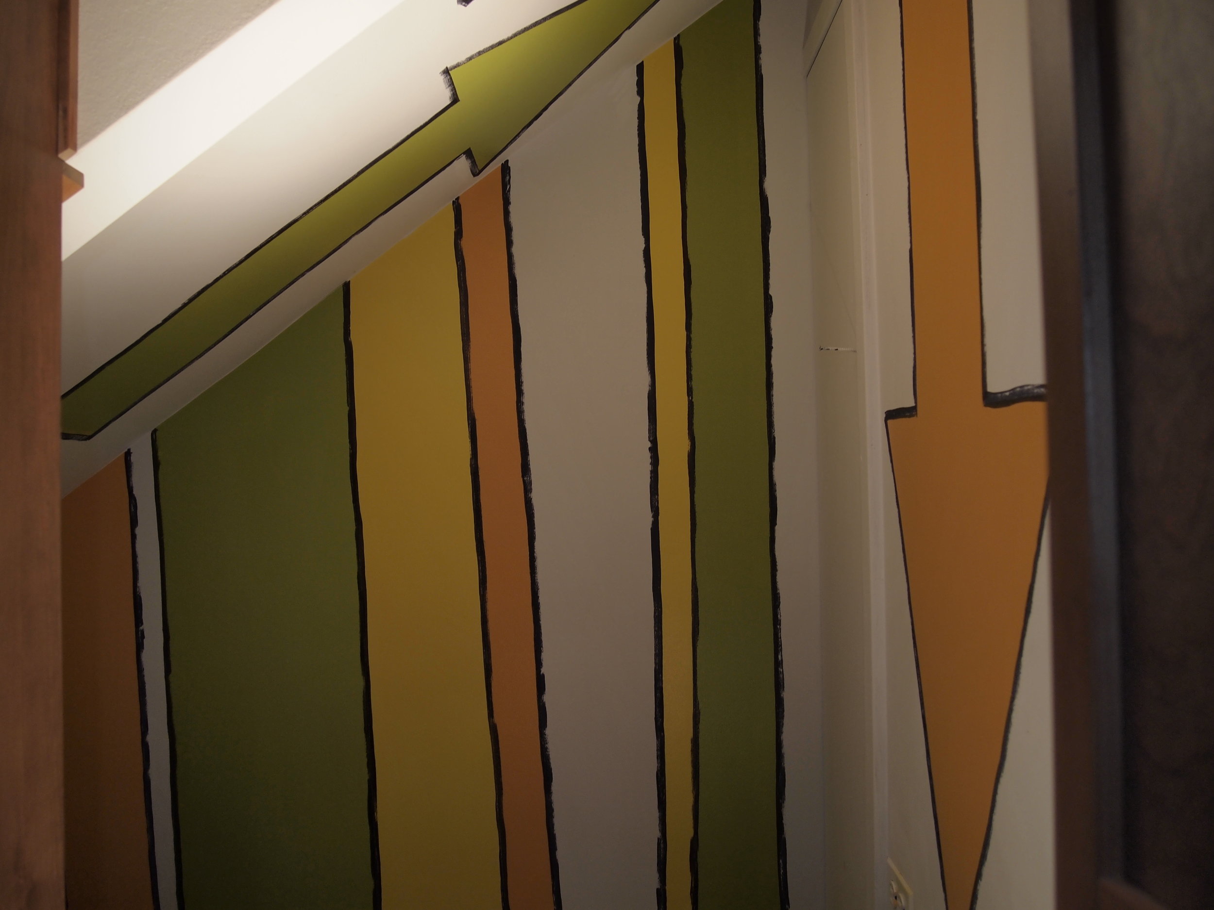  This is a tiny hideout for two little girls who play here. A custom cabinet hides the entrance to this space under the stairs. The arrows and lines create a secret forest and bring color, movement and a sense of children's drawings into this fun pla