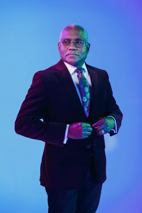 Man in navy suit on blue backdrop