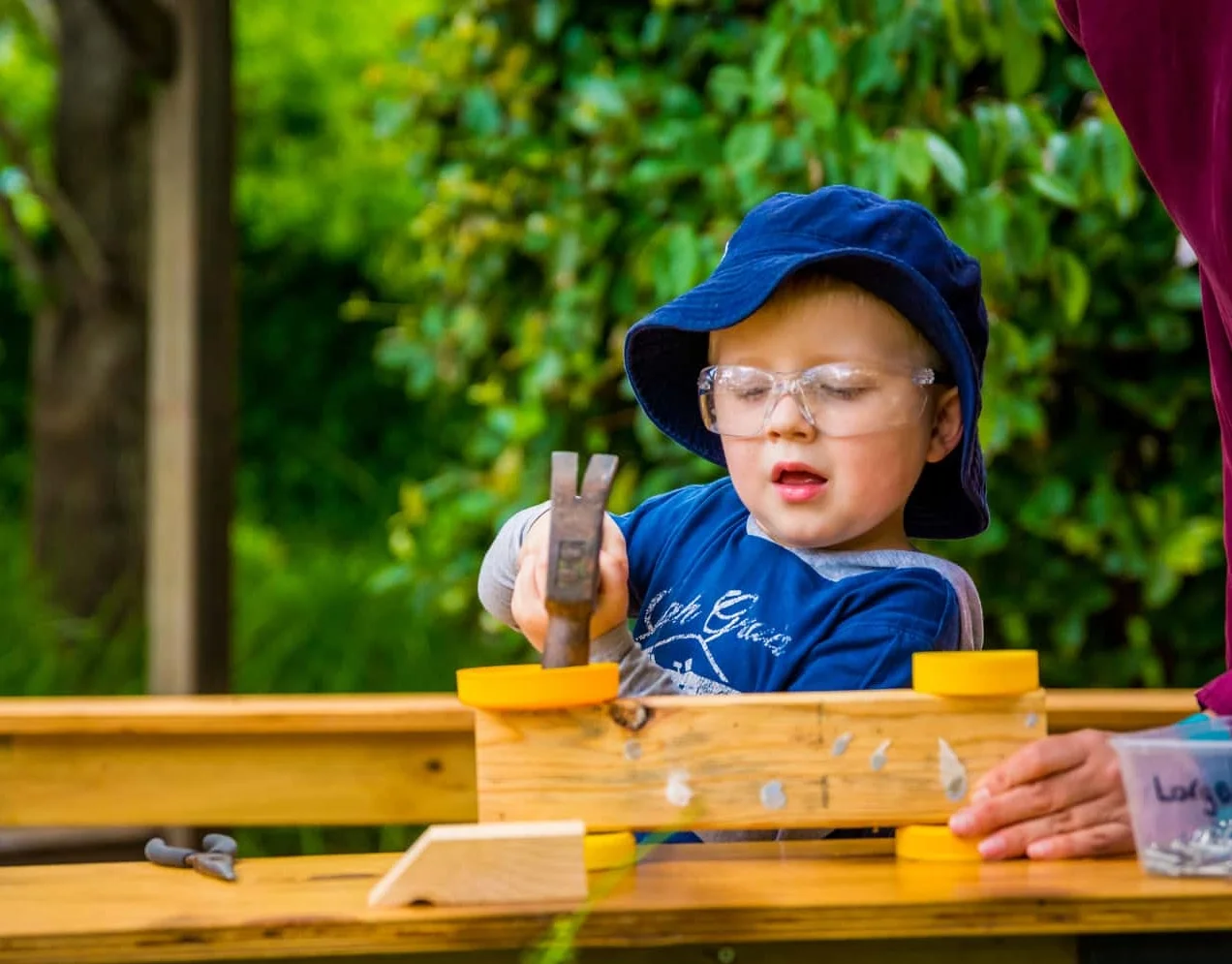 Chiselhurst boy doing woodwork all by himself with educator watching.