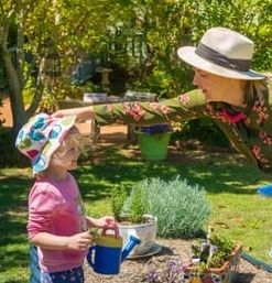 Educator helping keep little girls hat on while tending the Chiselhurst vegetable garden