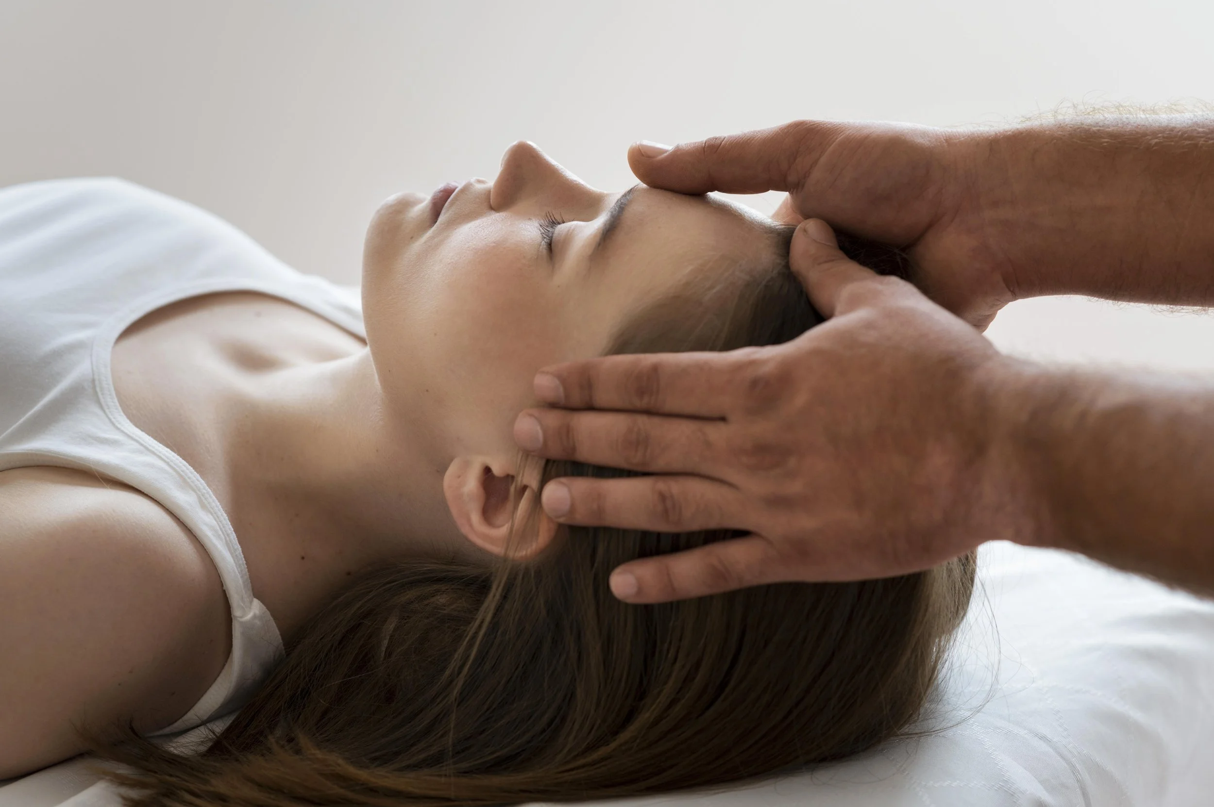 Craniosacral therapist gently holding client's head during a healing session
