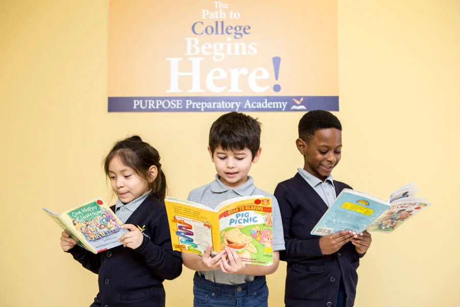 Three students reading books, posing for the camera.