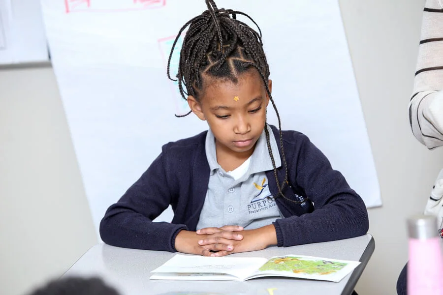 A girl sitting in her classroom, concentrating on her reading assignment