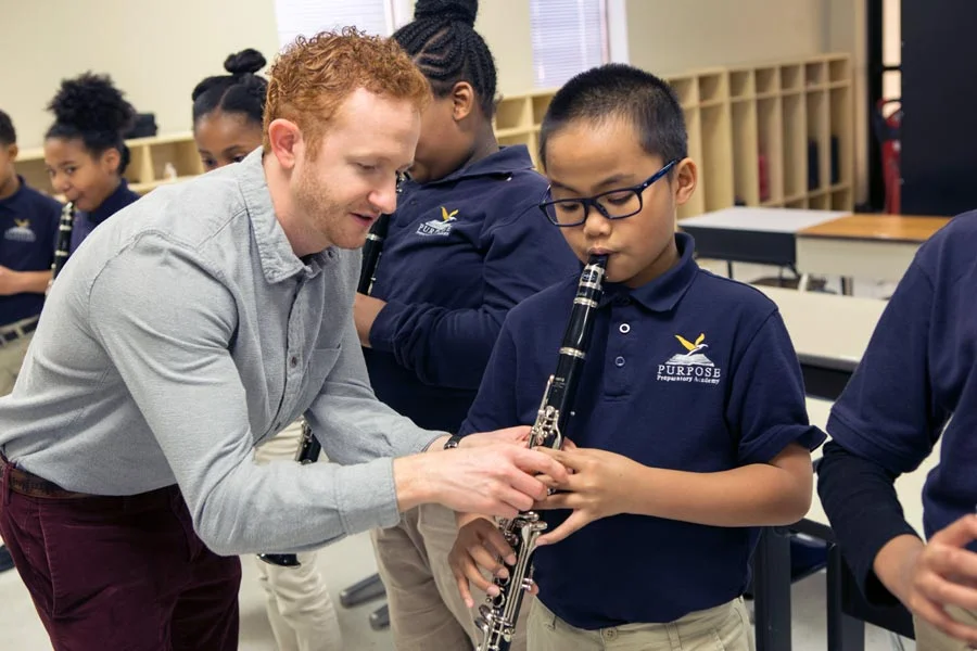 Music teacher helping a student with his instrument.