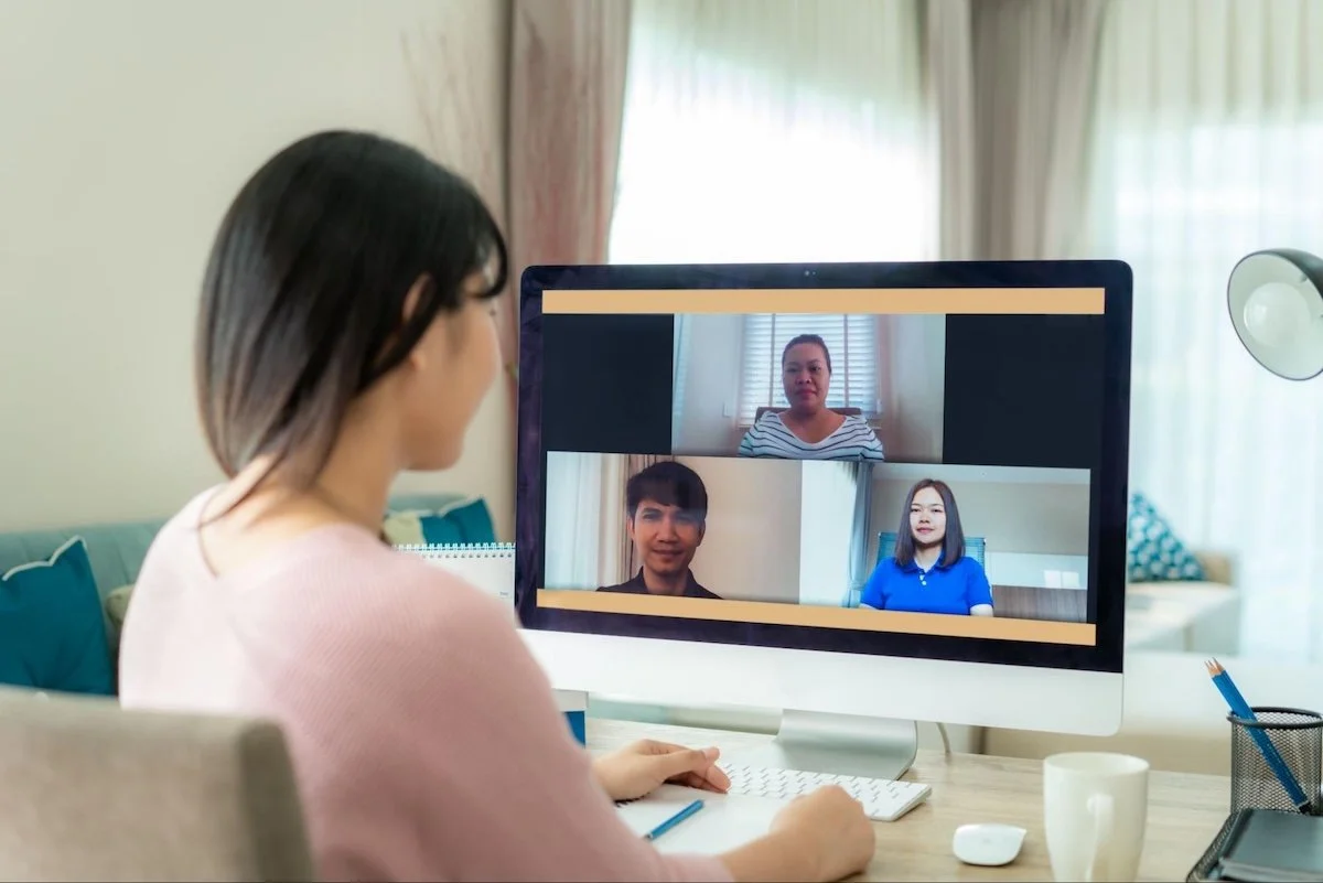 A woman is on a video call with three others at her home office.