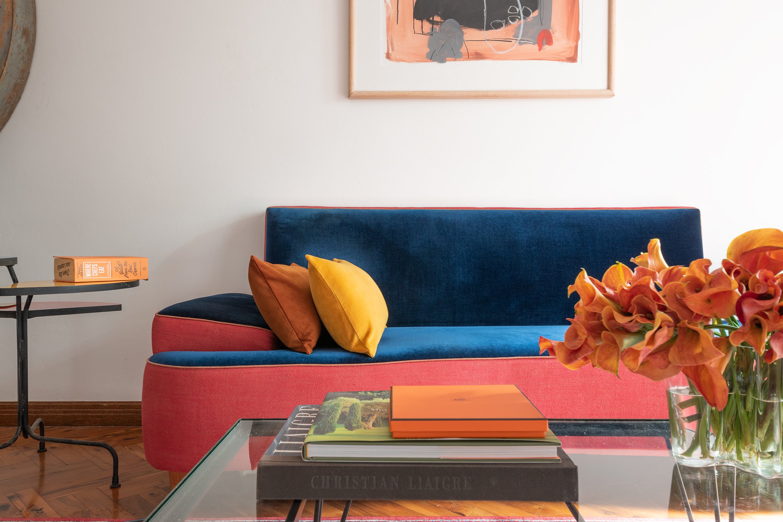 A reupholstered sofa in the original primary colours, featuring rich blue velvet and red linen upholstery. The reverse side of the red linen is used as the piping, adding a subtle yet striking detail. This piece, part of the client’s vintage furnitu