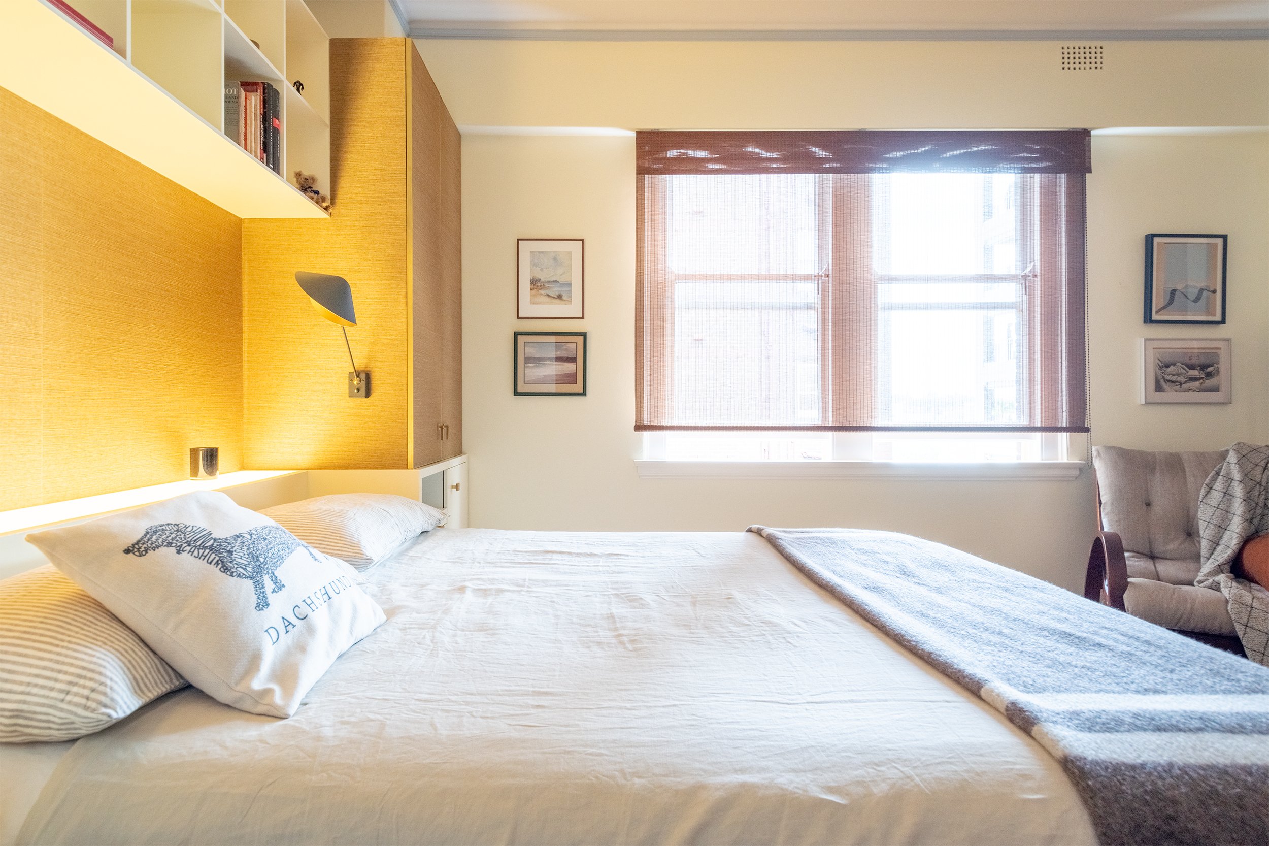 A different perspective of the bedroom, showing the bed with a view across the room towards the window. Japanese-made blinds complement the space, adding texture and softening the light while enhancing the bold, geometric design of the Art Deco room
