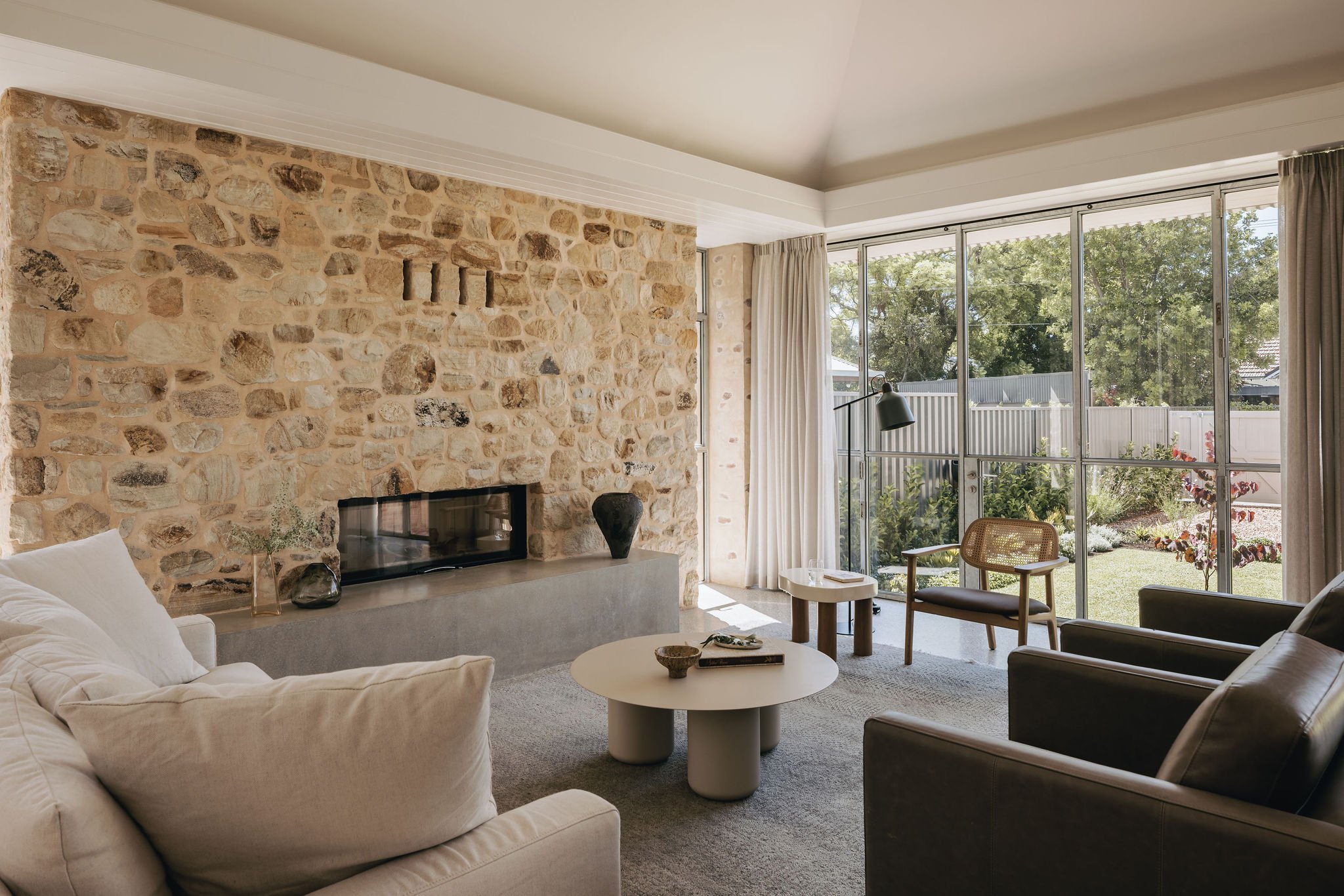 This stunning living room showcases a magnificent large fireplace, anchored by a striking stone chimney breast that commands attention. The solid concrete hearth adds a sense of durability and strength to the space. This design invites warmth and c