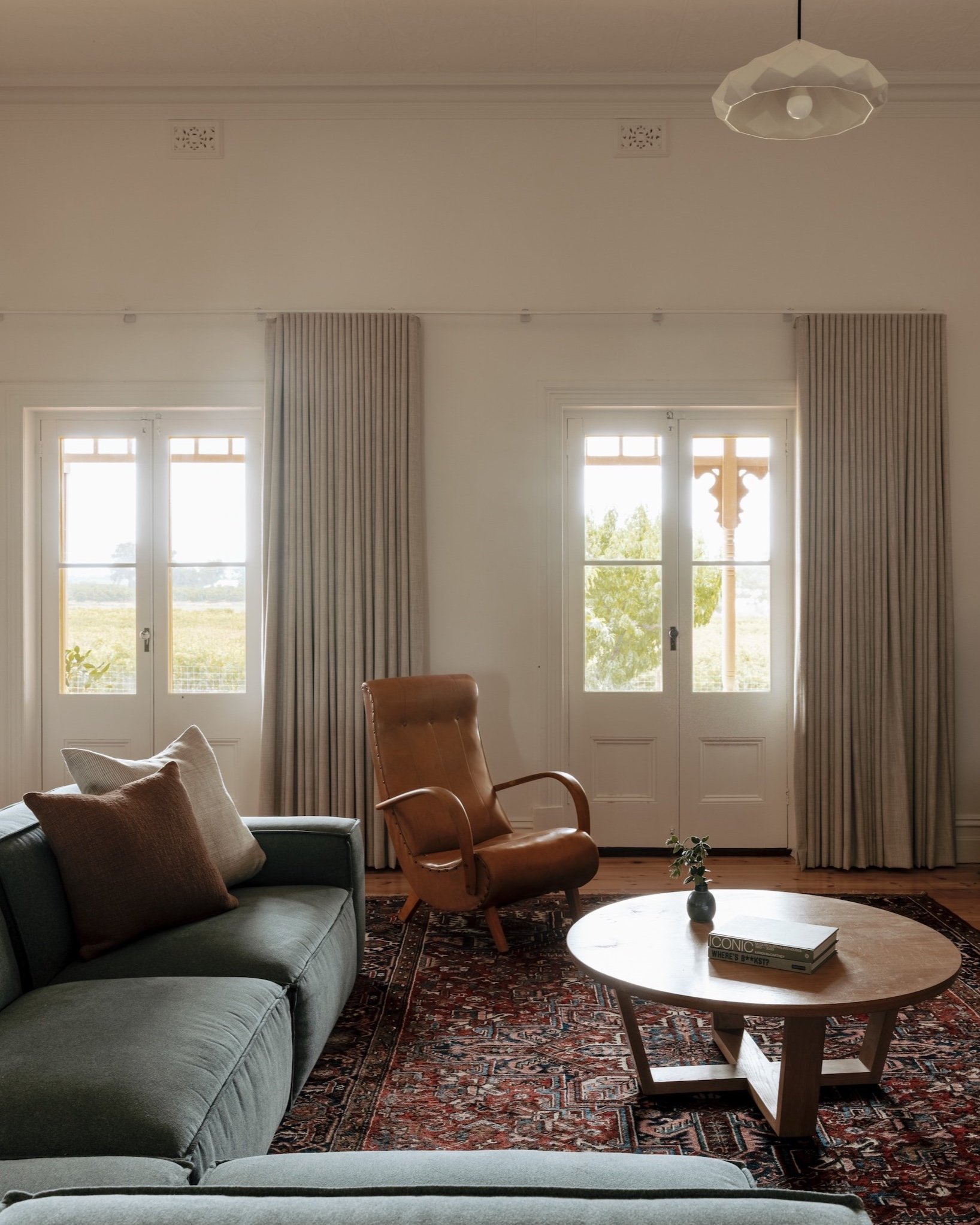 A look at the family room in the original part of the house, featuring new lighting and fresh paint that bring a contemporary touch to the space. The room offers a glimpse of the vines beyond the verandah, creating a seamless connection between the