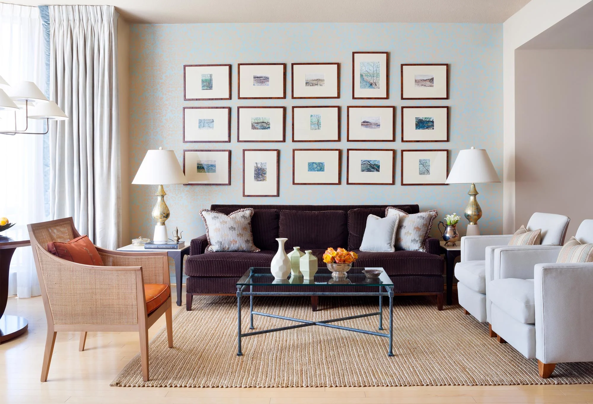 Light painted Living Room design with large brown sofa, single couches and glass top coffee table.