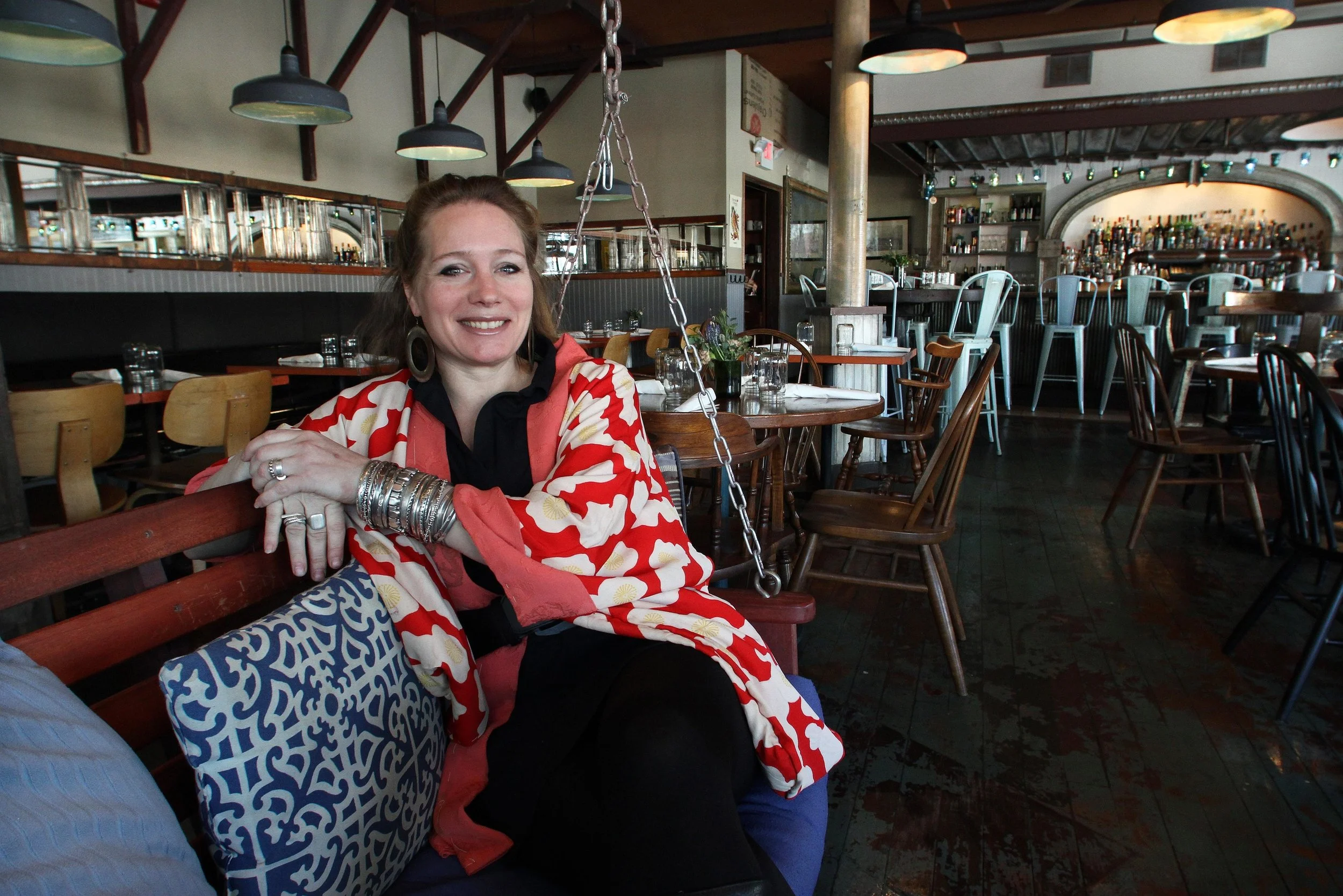 Kyla Coburn at The Grange, in Providence, which she designed about 2.5 years ago. Coburn, a recent inductee to the RI Design Hall of Fame, is known for a hip, eclectic look that re-purposes found items, such as this porch swing in The Grange’s waiting area. Photo Credit: The Providence Journal/Bob Breidenbach