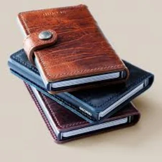 Secrid Wallet Secrid wallets are small on the outside but surprisingly big on the inside. Designed and made in Holland using traditional methods and locally sourced leather & aluminum, this compact wallet stores up to 6 cards in its RFID protected ultra-thin card chamber. The cards can be viewed and removed easily with the flick of a button. 6 more cards and plenty of cash can be stored in the leather pockets, all securely fastened with a stud closure. This wallet is compact, secure and perfect for someone looking for the latest in wallet tech with old-school style.
