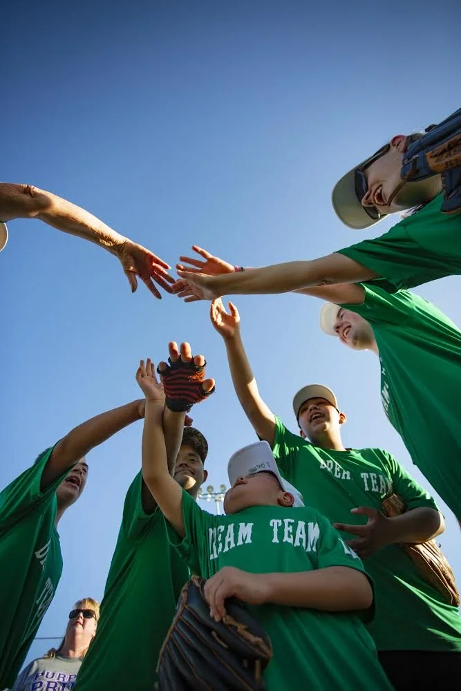  Members of the Dream Team raise their hands and cheer following a game at HermistonÕs Field of Dreams on Tuesday, May 4, 2021. 