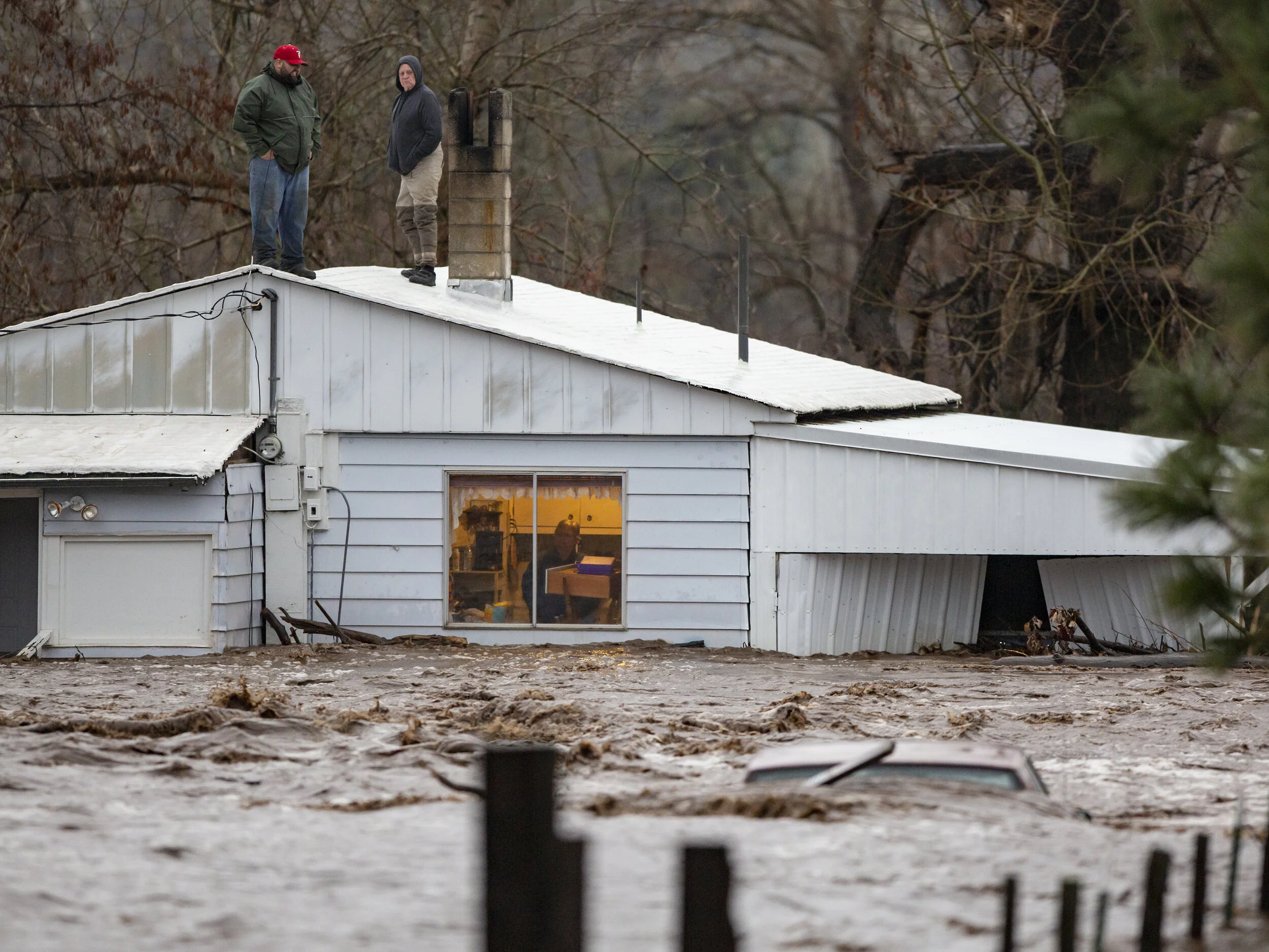  Nate Fuller and Archie Morrow await rescue on the roof of a home in Thorn Hollow. The pair were stranded when they attempted to rescue the elderly couple who was stuck in the house as waters from the Umatilla River began to rise. According to a fami