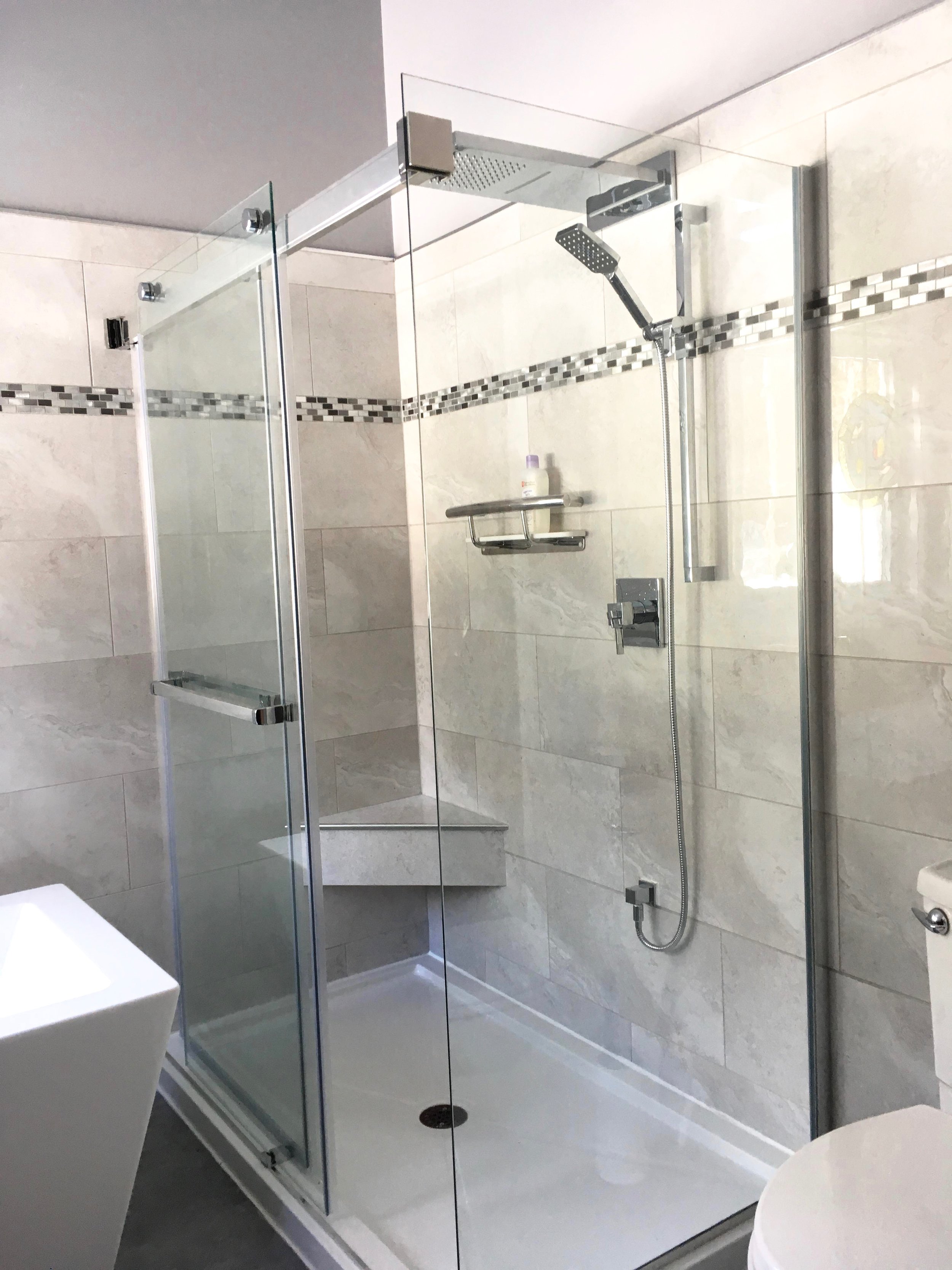 Free-standing shower stall with custom glass for 2 walls. Built-in bench