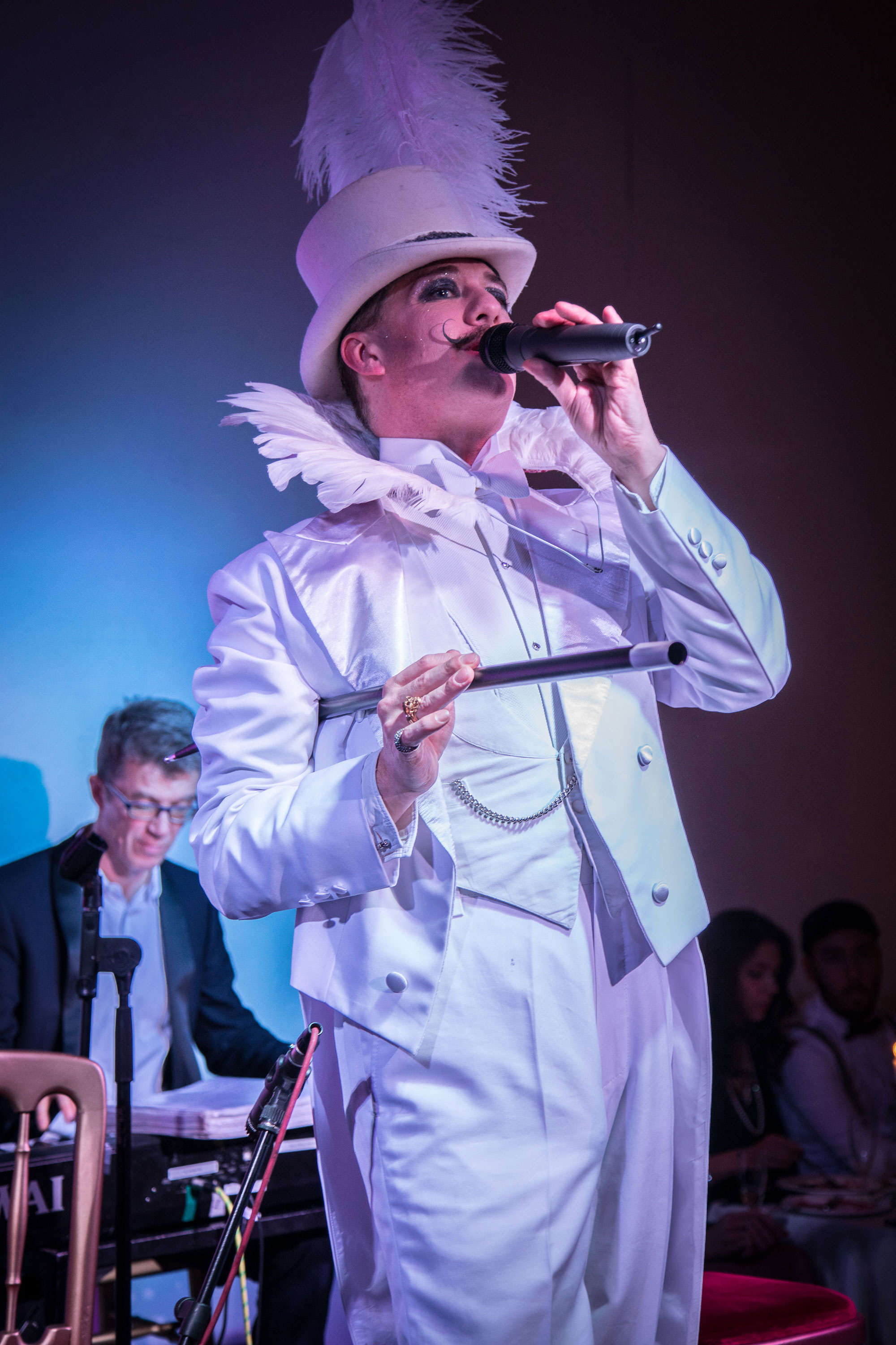 Cabaret host Champagne Charlie in a white suit