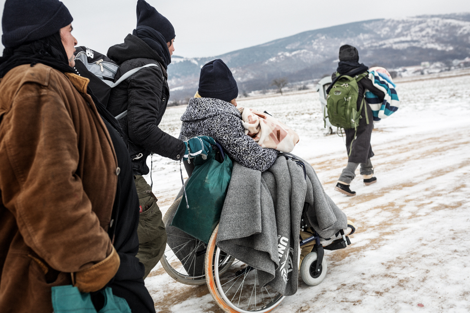  A family crosses the Balkans route pushing the wheelchair of a family member, Serbia, January 2016. People with disabilities and their families suffered a longer and more costly journey and were more at risk of falling into mafia networks. 