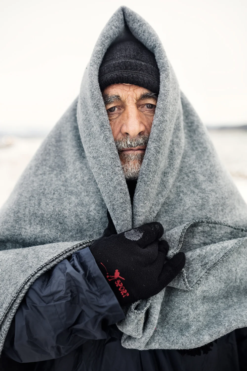  An elderly man covers his head with a blanket to protect himself from subzero temperatures next to Miratovac, Serbia, January 2016. 