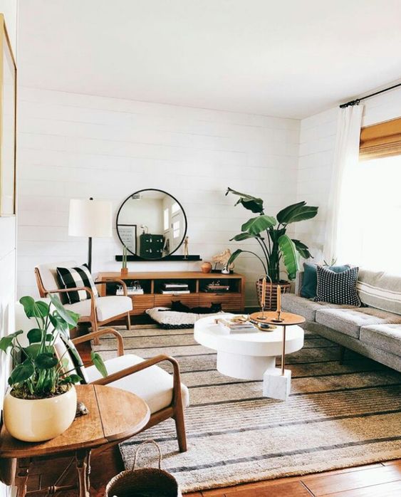 Some good-sized potted plants, natural wood and stone, and curved furniture + accent pieces make this living room an inviting place to rest with a cup of coffee and a book, or to hang out with friends.