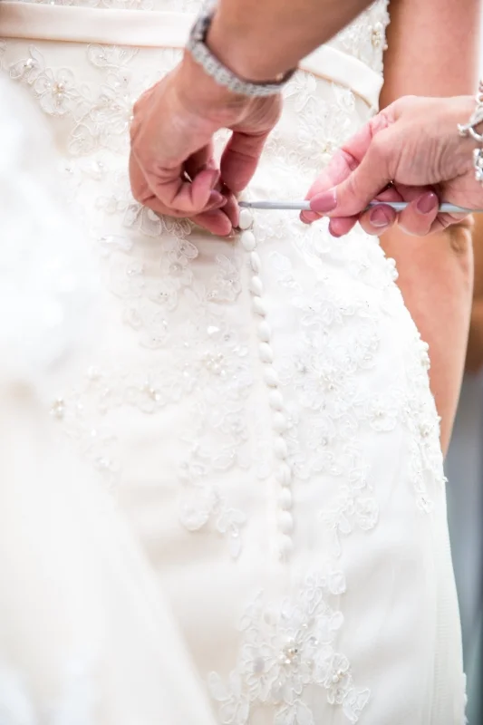 Wedding planner helping her bride in to her dress