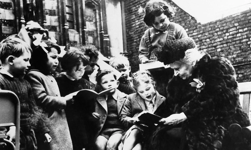 Dr. Maria Montessori reading with children.