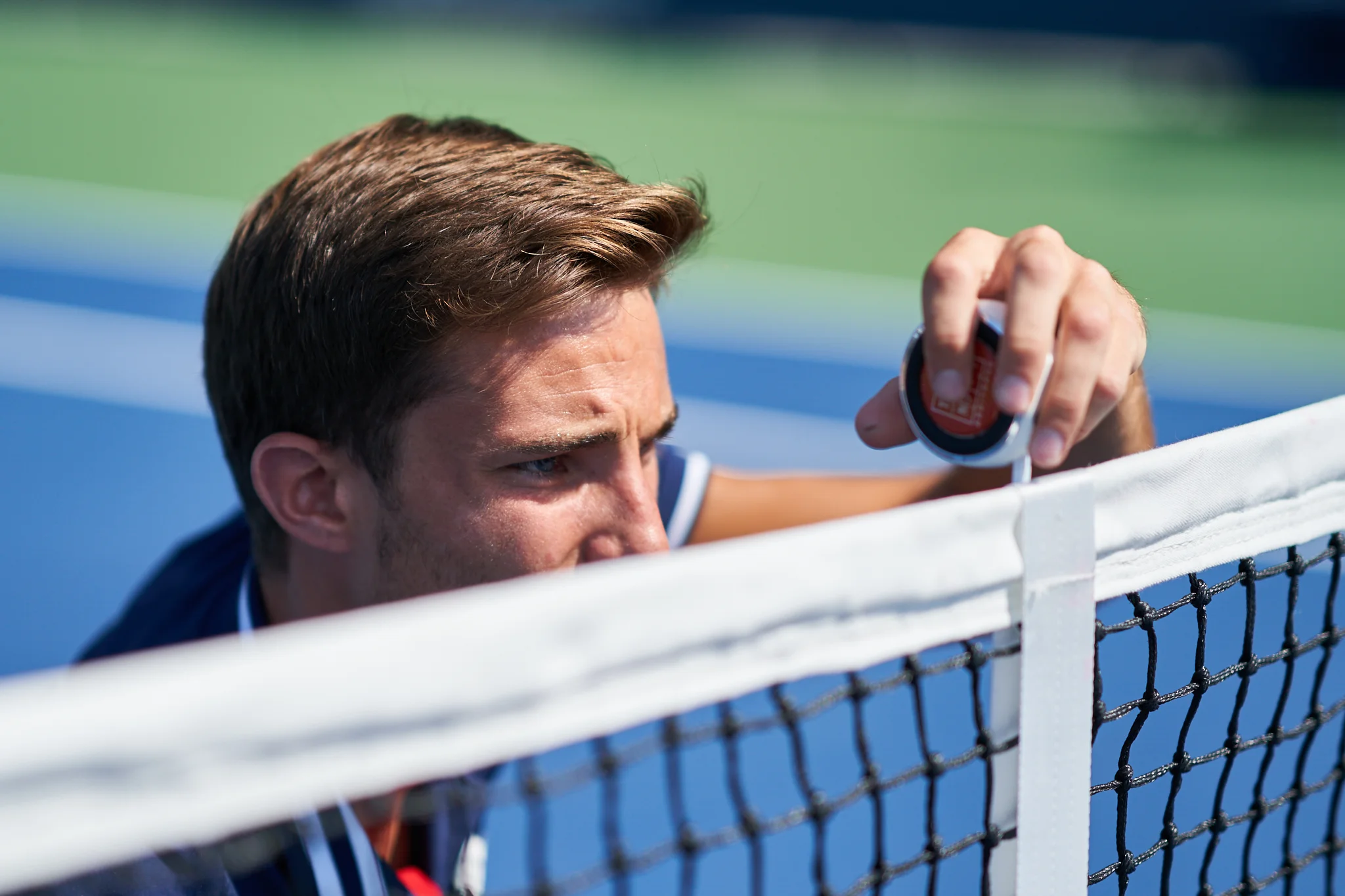 Chair umpire Tim Mevel measures the height of the net before second round play on Court 6. Sony A9, Sony 85mm f1.4 GM