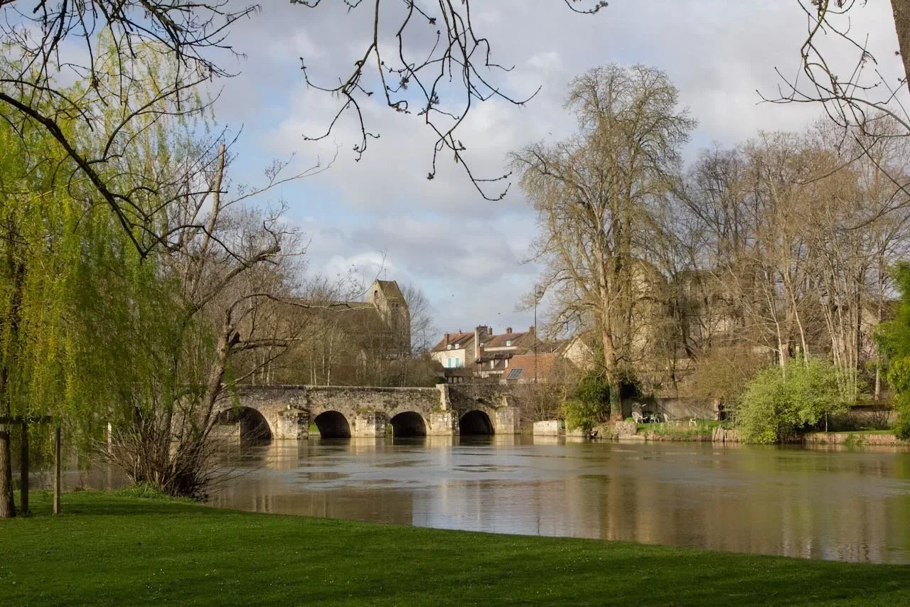 Arched Roman bridge over river in early spring in village