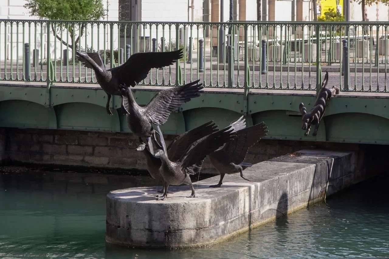 Sculpture by river of flying geese and dog
